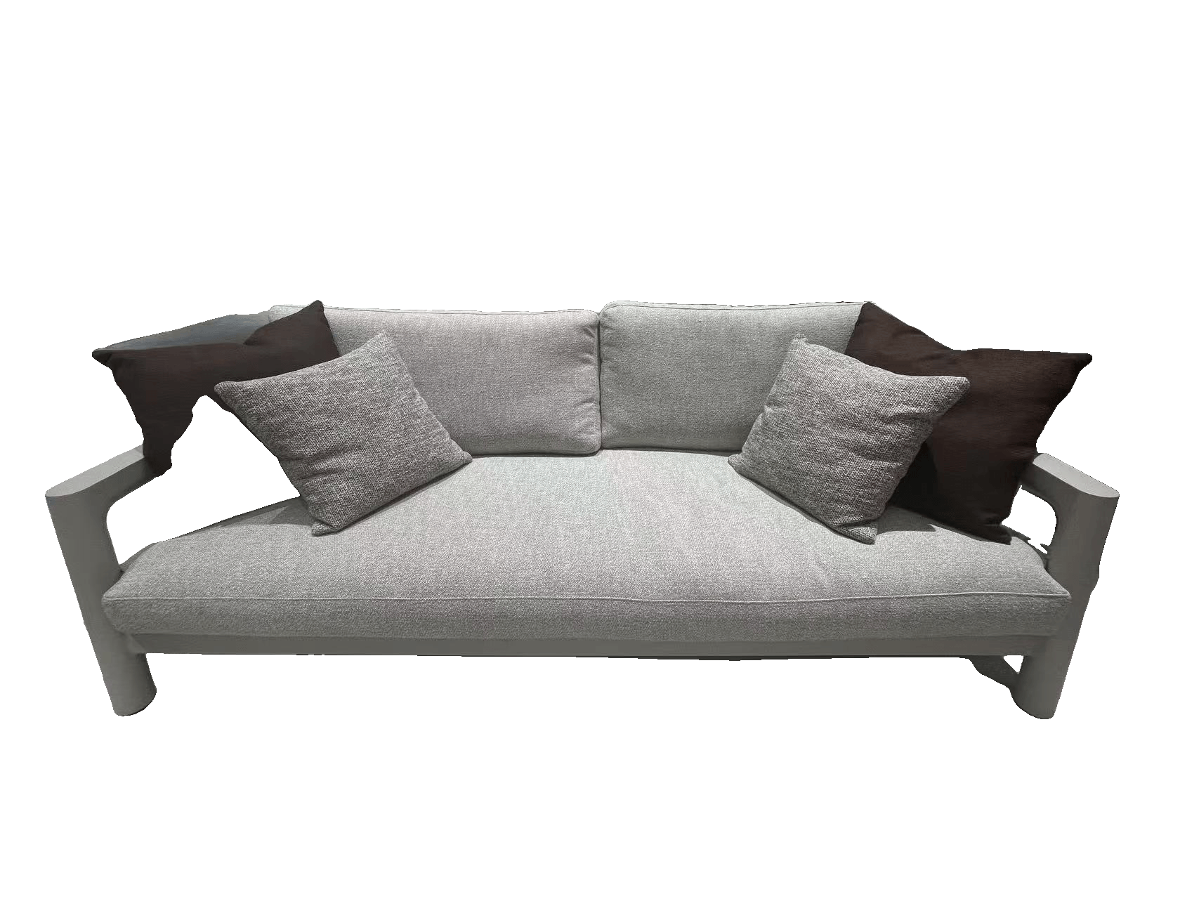A light grey outdoor armchair with a dark brown throw pillow is placed on a textured light grey rug in a showroom setting.