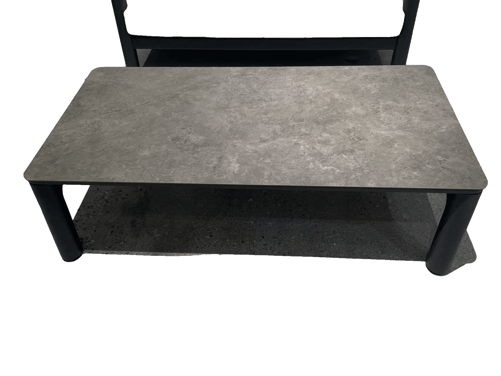 A rectangular outdoor coffee table with a dark gray, textured top and four sturdy, dark gray legs is shown on a speckled gray floor.